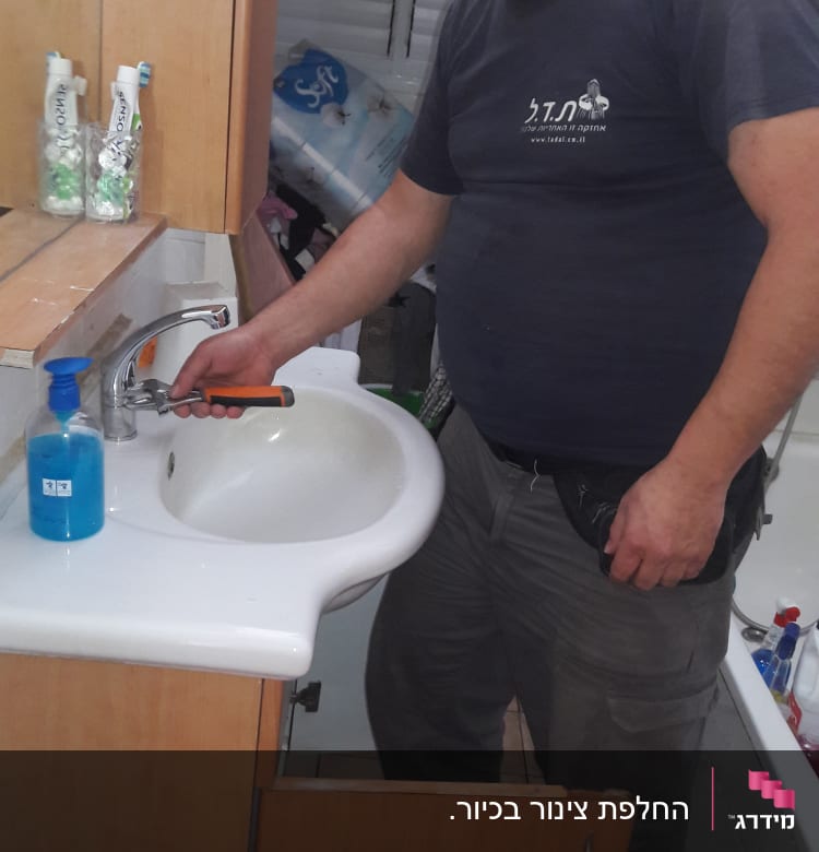 אדם מחזיק מפתח ברגים ליד כיור בחדר אמבטיה